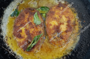 Surmai fish fillets sizzling in hot oil in a frying pan for Surmai Fish Fry Recipe